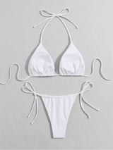 White halterneck bikini top and tie-side bottoms laid flat, detail view.