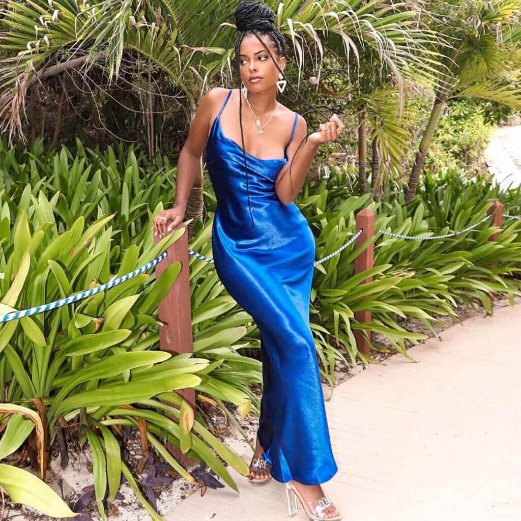 Woman in a royal blue satin slip dress posing outdoors
