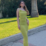 Woman wearing a lime green cowl neck maxi dress with spaghetti straps, standing outdoors.