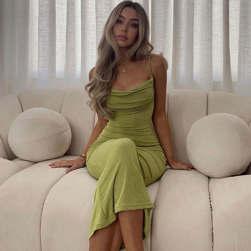 Woman wearing a lime green cowl neck maxi dress with spaghetti straps, sitting on a couch indoors.