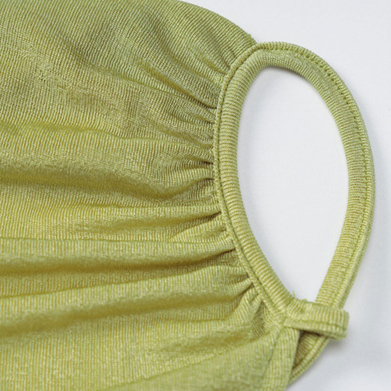 Close-up of the ruched detail on the shoulder strap of a lime green dress.