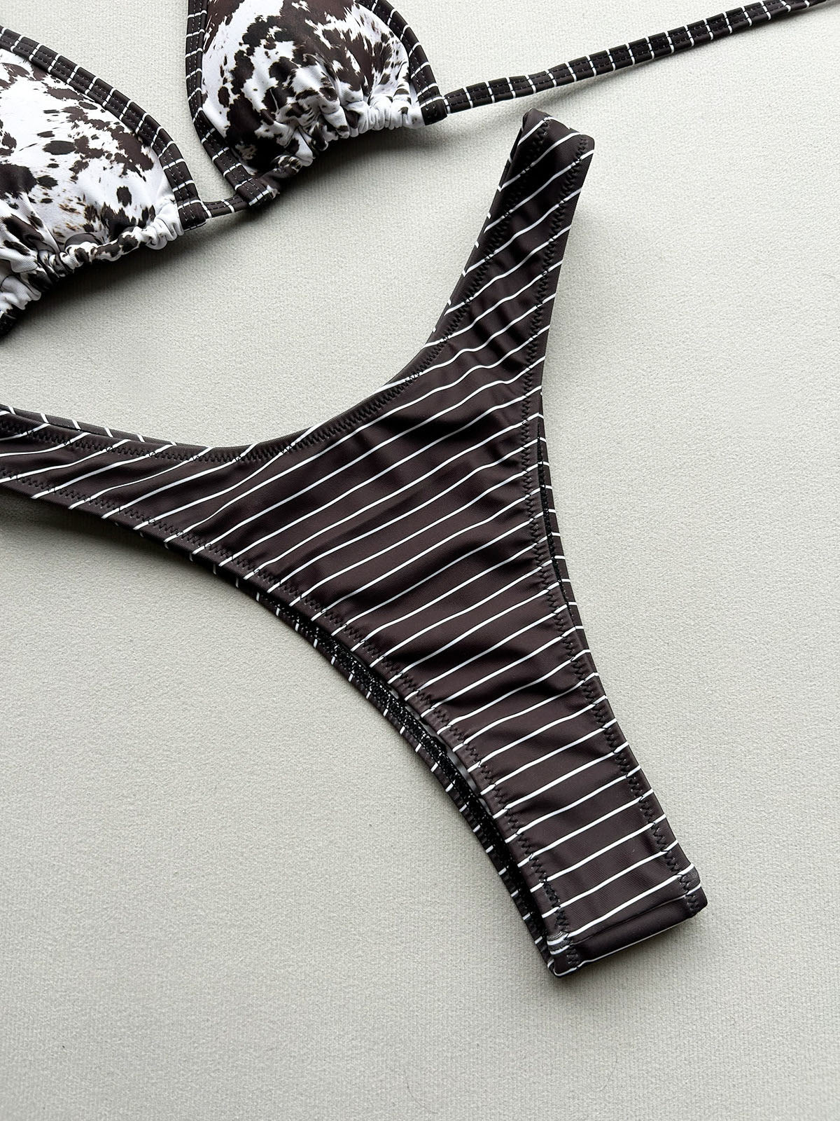 Close-up of bikini bottoms with a dark brown and white stripe pattern and contrast trim.
