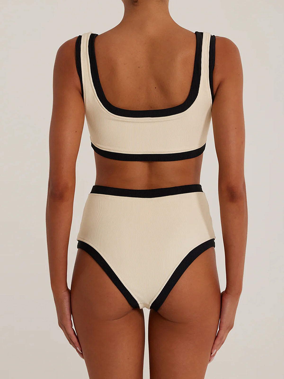 Woman wearing a cream and black ribbed bikini set, back view.