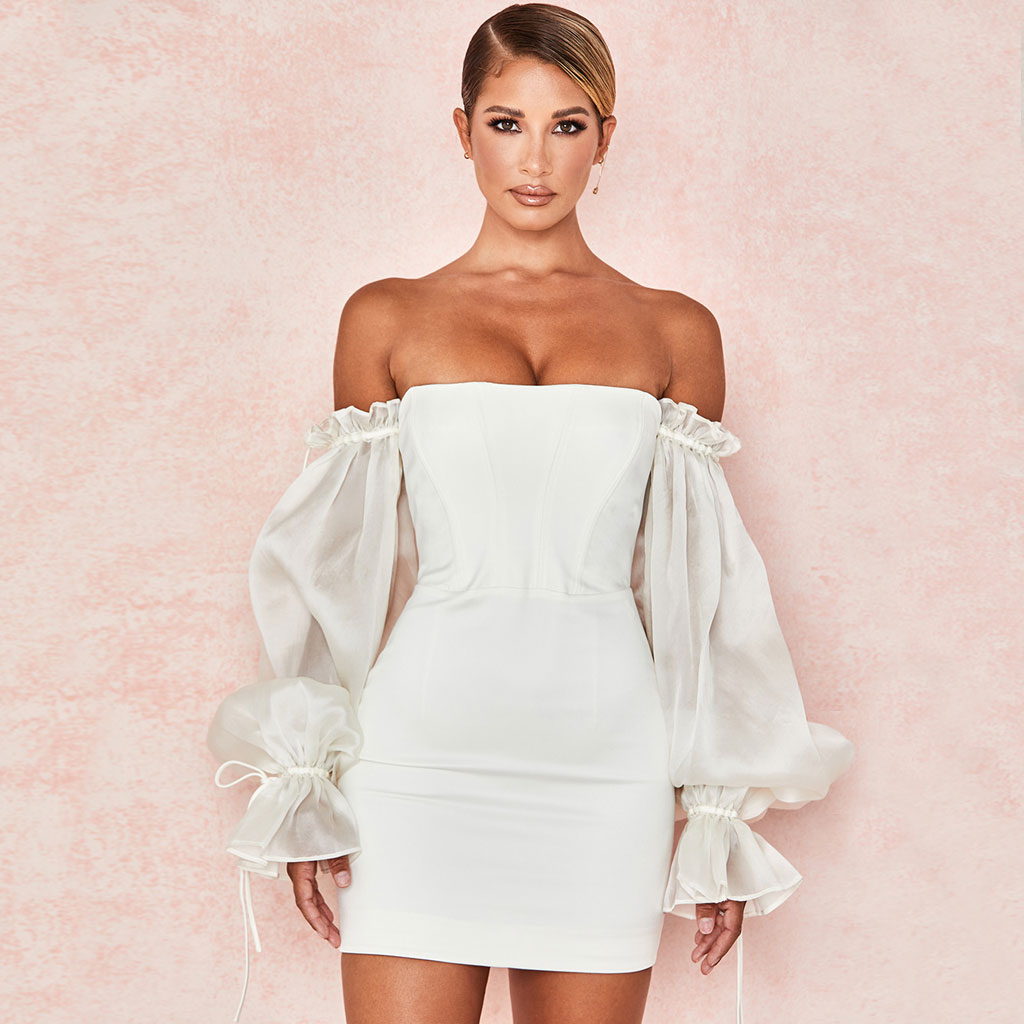Woman wearing a white off-the-shoulder mini dress with sheer puff sleeves
