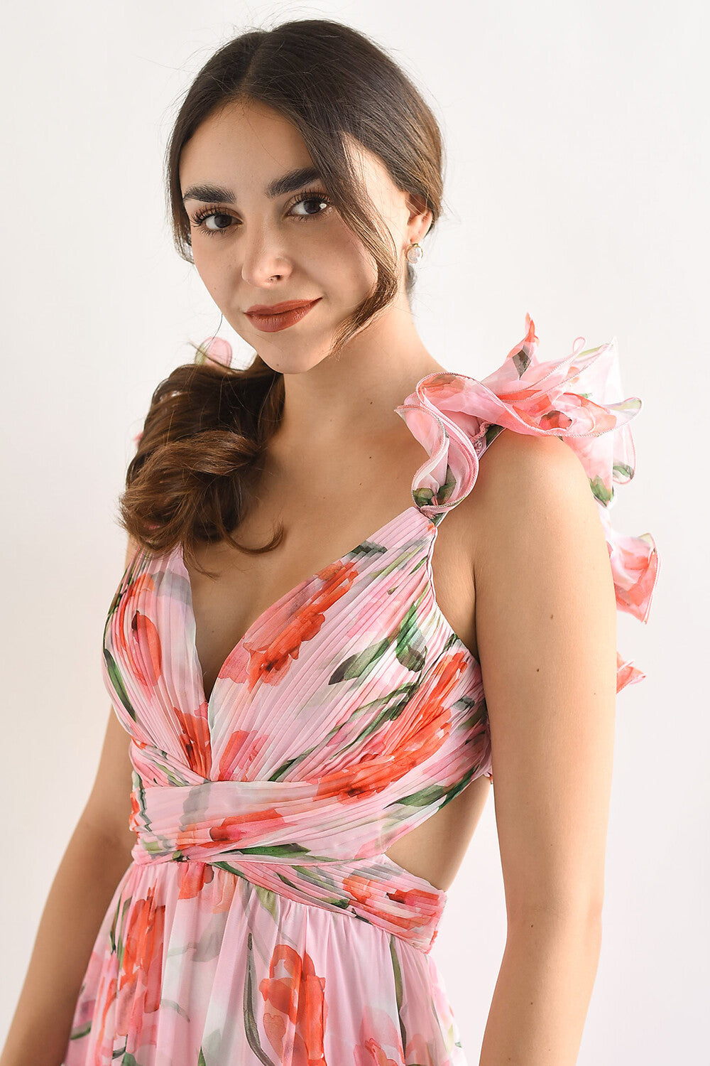 Close-up of the bodice of a pink floral print maxi dress, highlighting the plunging neckline, ruffled shoulder straps, and cut-out sides.