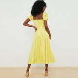 Back view of a woman in a yellow floral print midi dress with puff sleeves and a high slit.