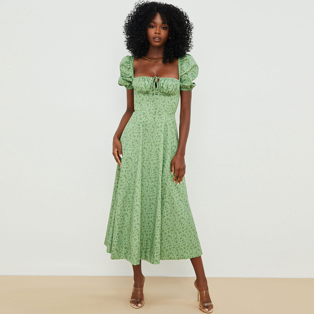 Woman wearing a green floral print midi dress with puff sleeves and a square neckline.