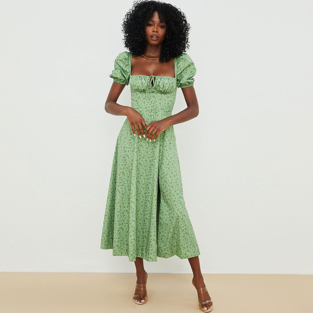 Full-length view of a woman in a green floral print midi dress.