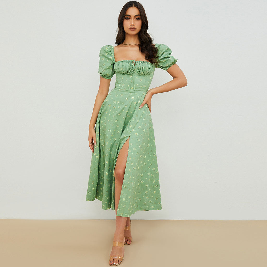 woman wearing a green floral puff sleeve midi dress with a thigh-high slit