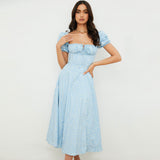 Woman wearing a light blue floral print midi dress with puff sleeves and a square neckline, standing against a white background.