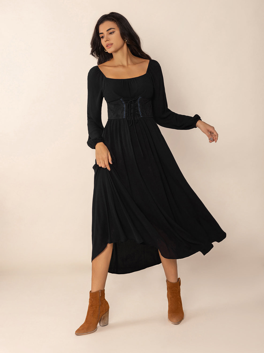 Woman wearing a black midi dress with a square neckline, long puff sleeves, and a corset-style waist detail, twirling the skirt to show its flowy nature.