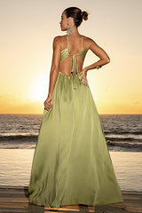 Back view of a woman in a lime green halter maxi dress with an open back and adjustable tie, with the ocean and sunset in the background.