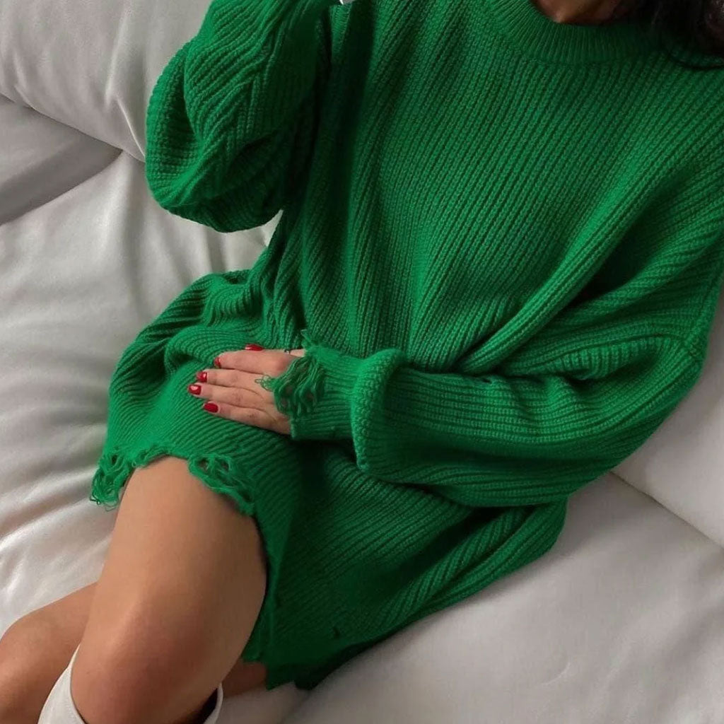 Woman posing in a green distressed oversized knit tunic sweater and white boots