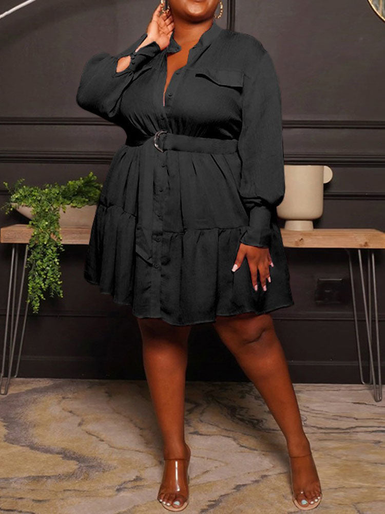 Woman wearing a black shirt dress with a belted waist and tiered hem.