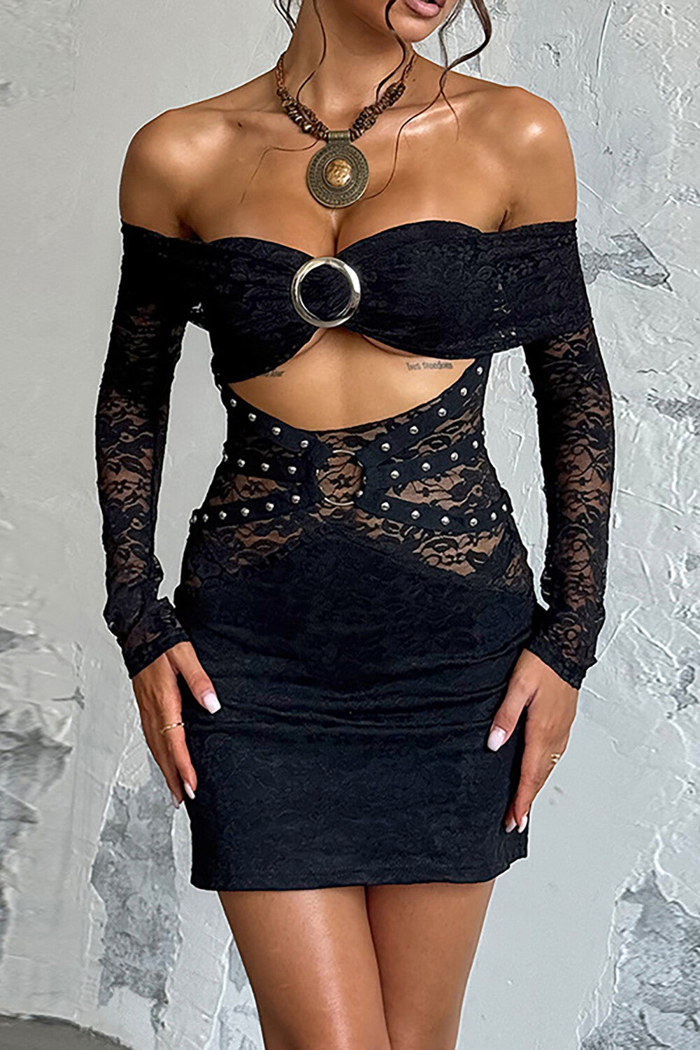 Woman wearing a black off-the-shoulder lace dress with long sleeves and a cut-out detail.