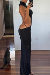 Woman in a long black sleeveless dress with an open back and cut-out sides, accessorized with an arm cuff and rings.
