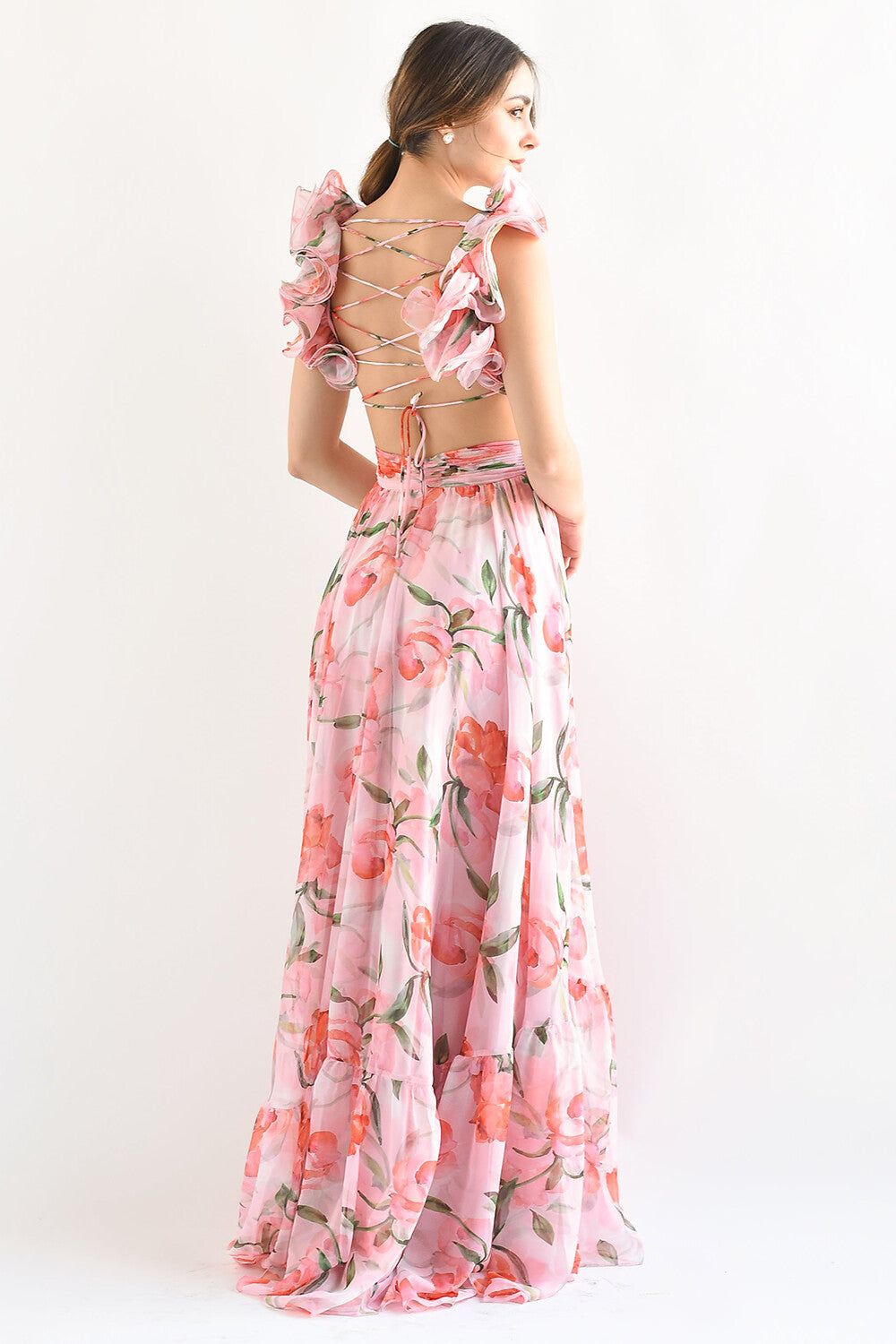 Back view of a woman in a pink floral print maxi dress, showcasing the criss-cross back detail and ruffled shoulder straps.
