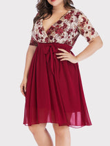 Side view of a plus size woman showcasing the fit of the burgundy floral print lace wrap dress