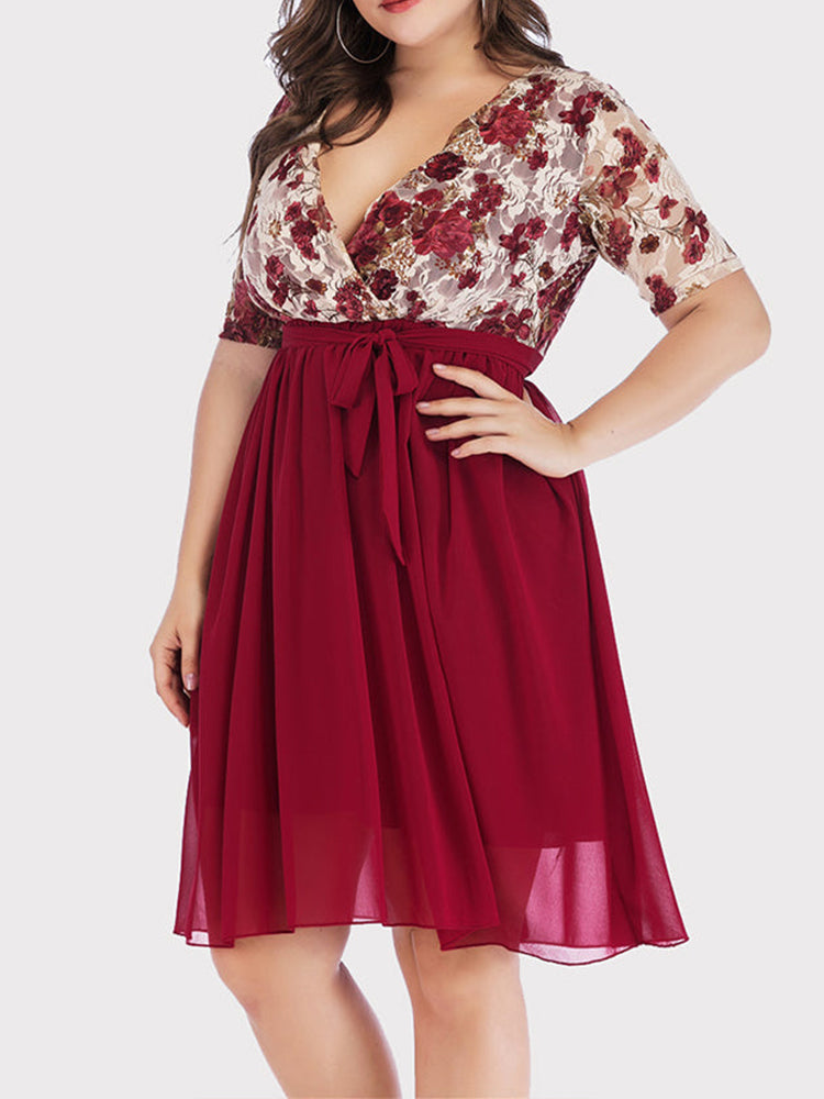 Side view of a plus size woman showcasing the fit of the burgundy floral print lace wrap dress