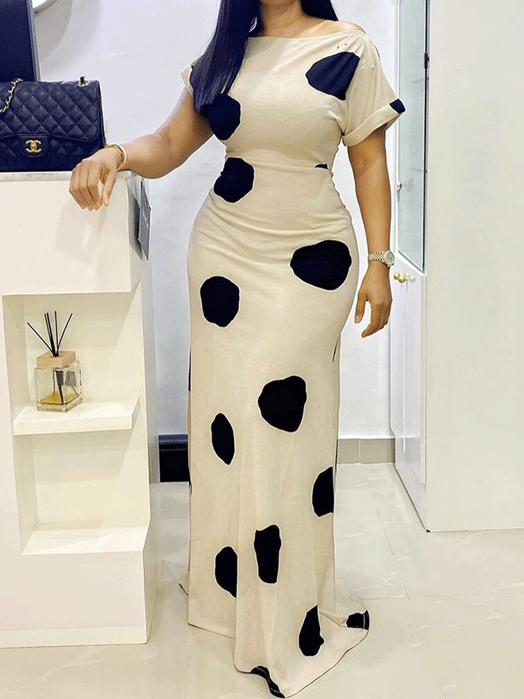 Woman wearing a cream and black polka dot maxi dress with short sleeves and an off-the-shoulder neckline, standing indoors.
