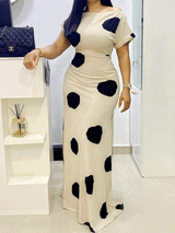 Woman wearing a cream and black polka dot maxi dress with short sleeves and an off-the-shoulder neckline, standing indoors.