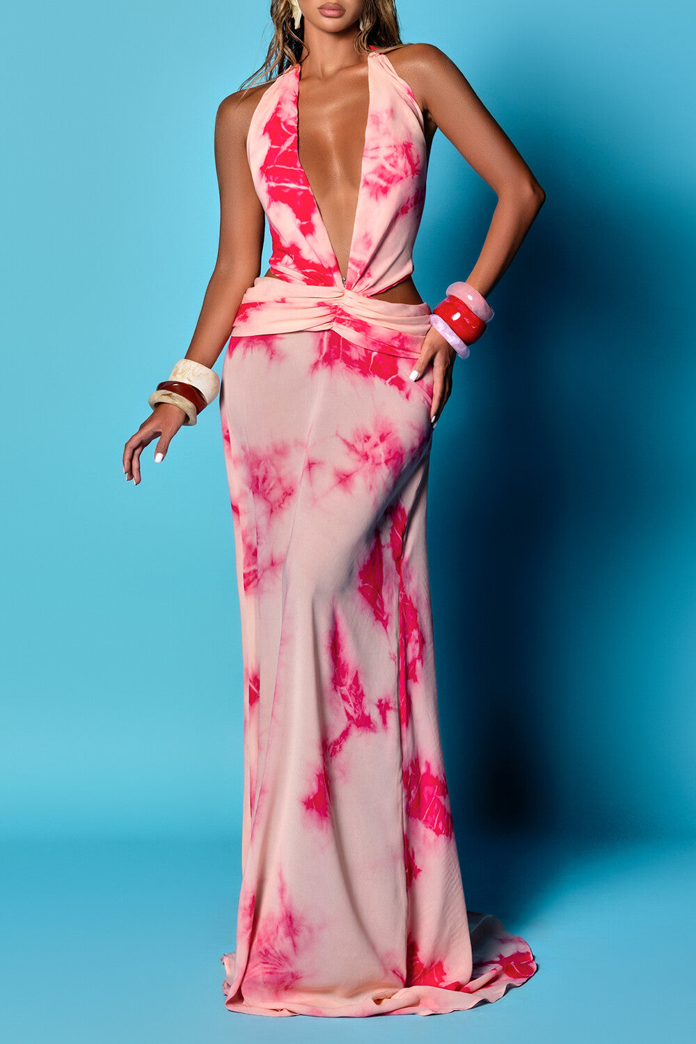 woman wearing a light pink and magenta tie-dye maxi dress with a plunging neckline and cut-out sides