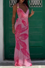Woman wearing a flowing pink floral maxi dress with a halter neckline, standing in front of a green door.
