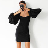 Woman in a black mini dress with puff sleeves taking a selfie