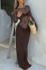 Woman in a long brown lace dress standing next to a ladder.