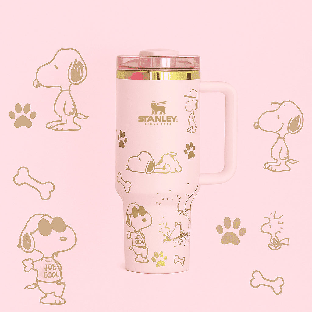 Stanley 40oz insulated tumbler featuring Snoopy illustrations, blue paw prints and bone icons, white body with white ergonomic handle