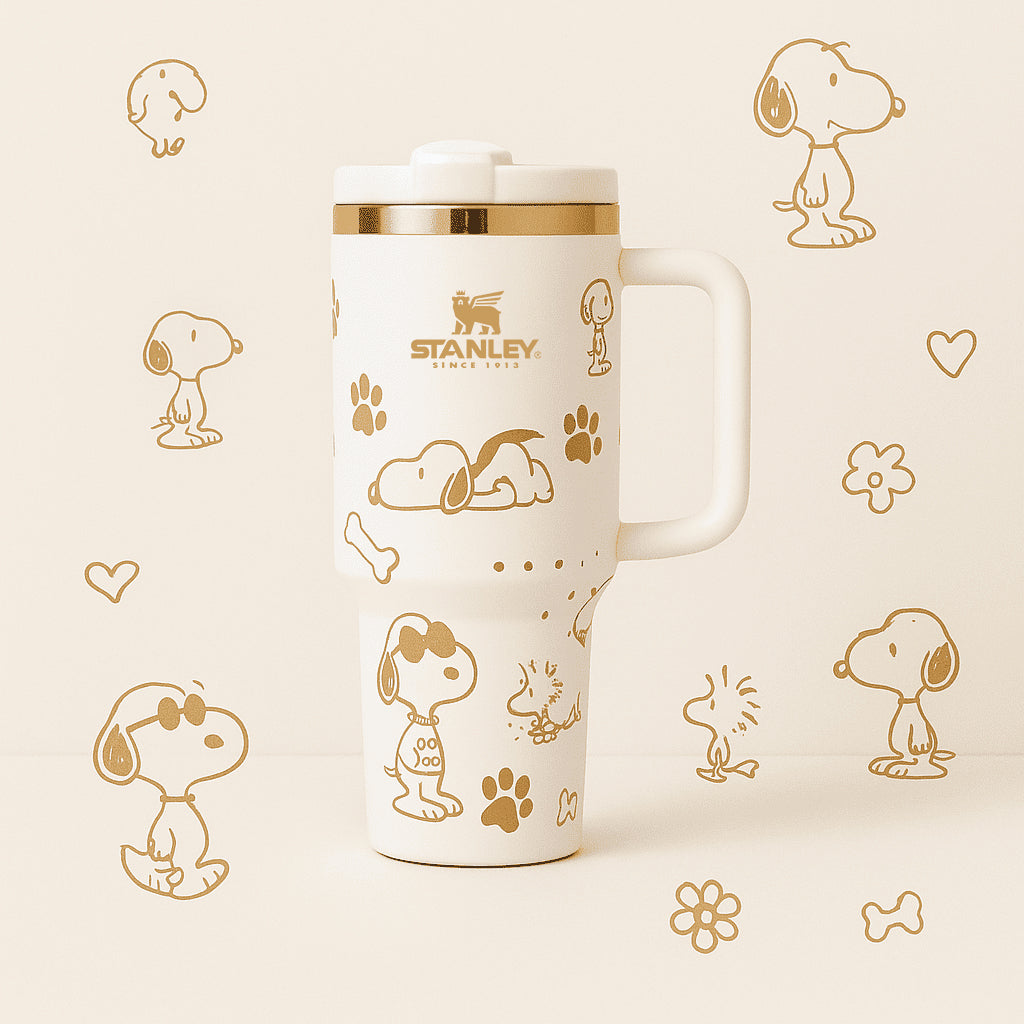Stanley 40oz insulated tumbler featuring Snoopy illustrations, blue paw prints and bone icons, white body with white ergonomic handle