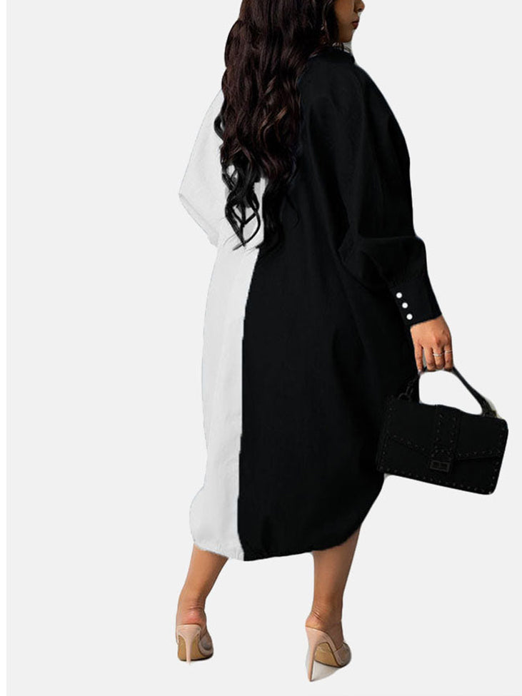 Back view of a woman wearing a black and white color-blocked oversized shirt dress with button-down front and adjustable drawstring hem, holding a black handbag.