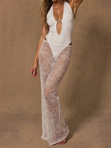 Woman in a white one-piece swimsuit with a sheer white lace maxi skirt, front view.
