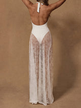 Woman in a white one-piece swimsuit with a sheer white lace maxi skirt, back view.