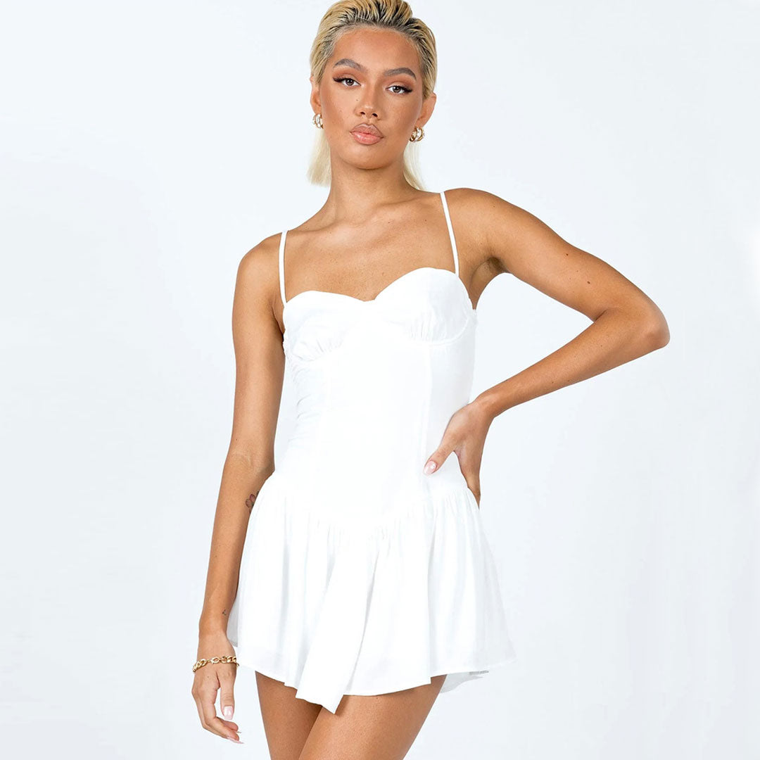 Woman wearing a white mini dress with spaghetti straps and a sweetheart neckline.