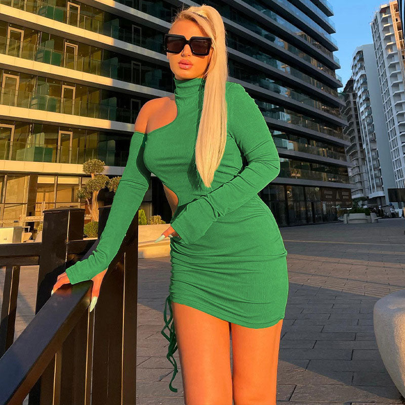 woman wearing a green long-sleeved mini dress with asymmetrical cut-outs and a drawstring hem, posing outdoors