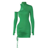 woman wearing a green long-sleeved mini dress with asymmetrical cut-outs and a drawstring hem, leaning on a railing