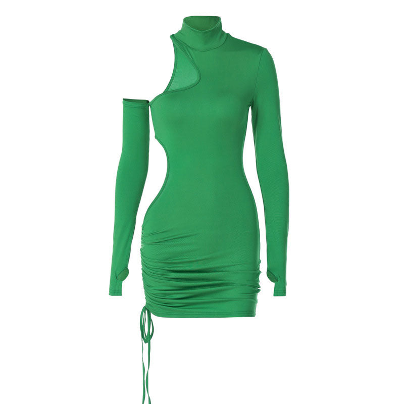woman wearing a green long-sleeved mini dress with asymmetrical cut-outs and a drawstring hem, leaning on a railing