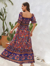 Woman in a blue floral off-the-shoulder maxi dress, showing the back view and spinning.