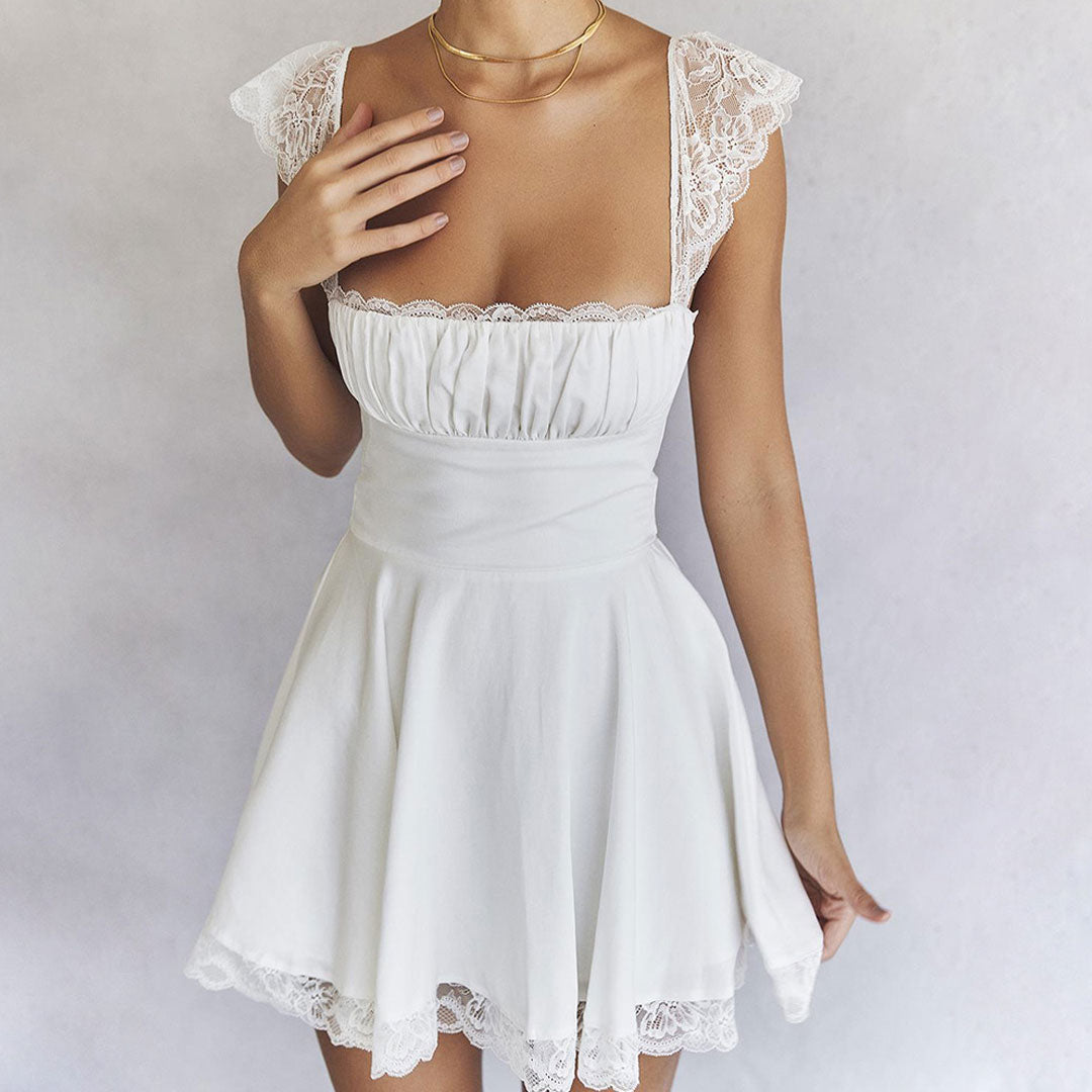 Close-up of a woman wearing a white mini dress with lace trim and a gold necklace