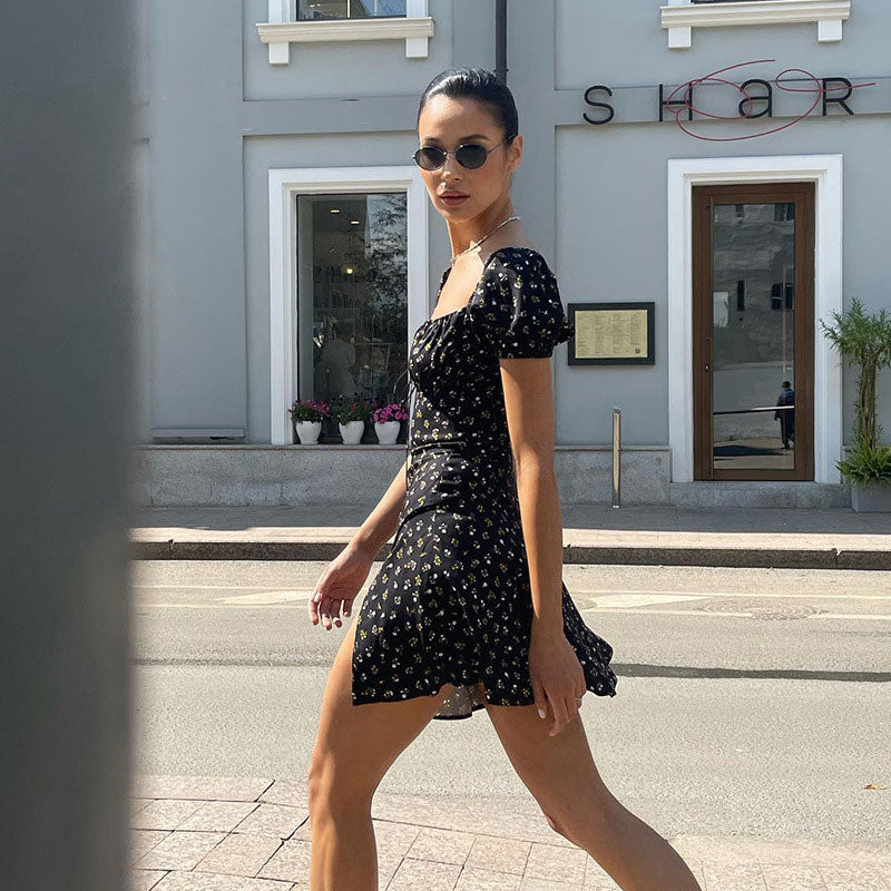 woman walking on a sidewalk in a black floral print mini dress with puff sleeves