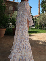Back view of a woman in a flowing white and blue patterned maxi cover-up