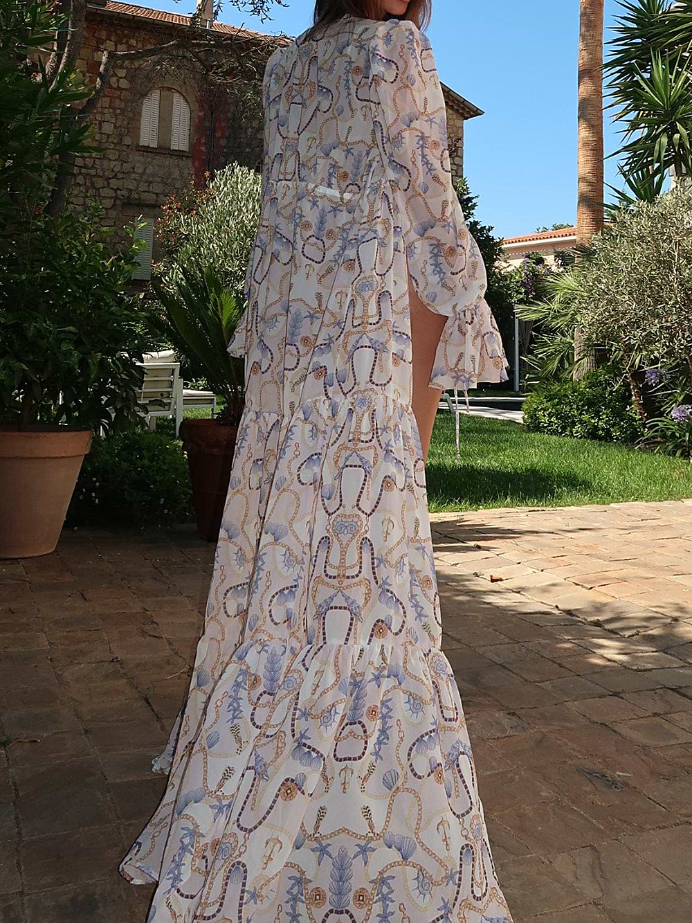 Back view of a woman in a flowing white and blue patterned maxi cover-up