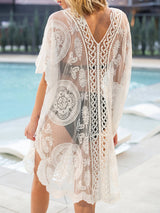 back view of a woman wearing a white lace kaftan over a black bikini by a pool
