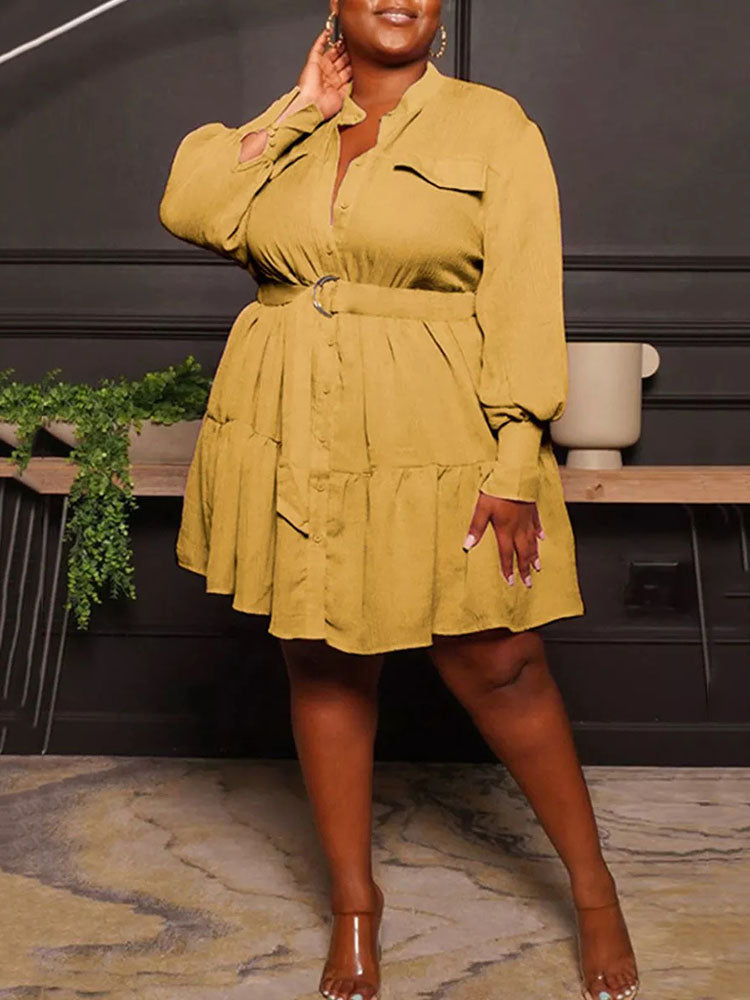 Woman wearing a mustard yellow shirt dress with a belted waist and tiered hem.