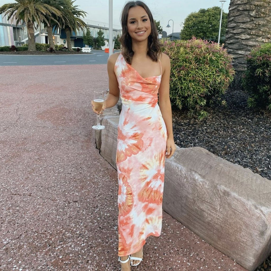 woman in orange and white tie-dye slip dress holding a champagne flute outdoors