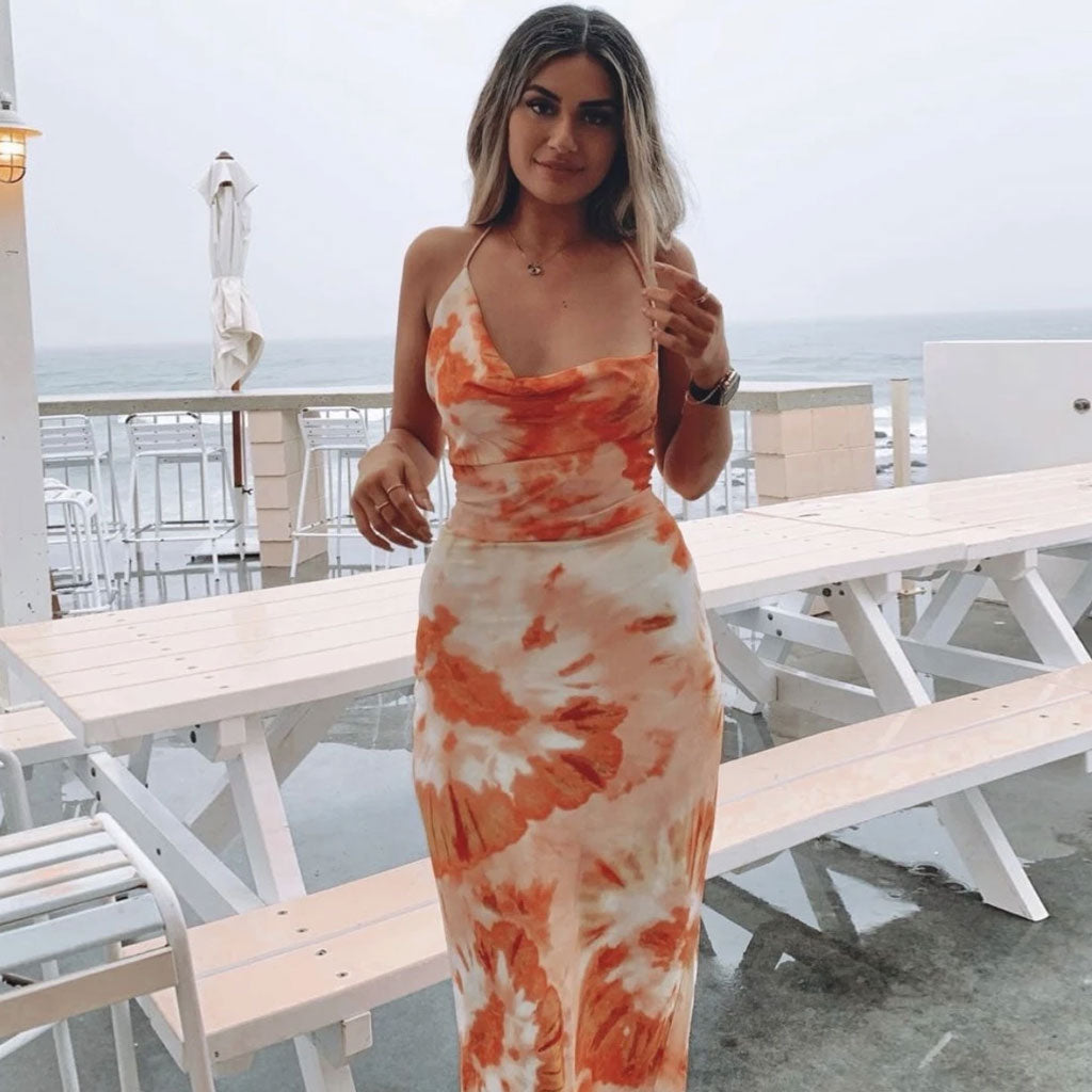 woman in orange and white tie-dye slip dress standing by the ocean