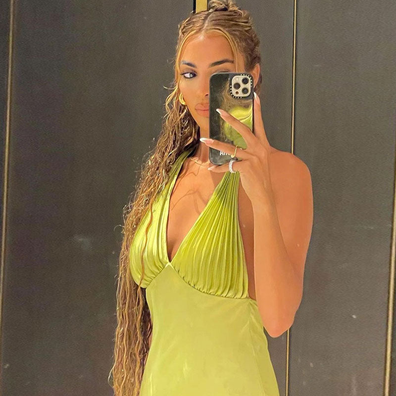 Close-up of a woman wearing a lime green satin halter midi dress, taking a selfie in a mirror.