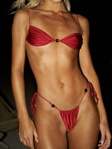 Woman wearing a red ruched bikini top with decorative hardware