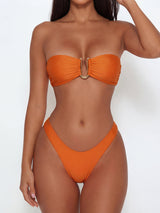 Woman wearing an orange strapless bikini with gold hardware